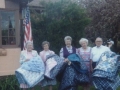 Left to right: Marie, Lois, Wanda, Eva, Holley. Holding quilts. Probably quilts made by these ladies.